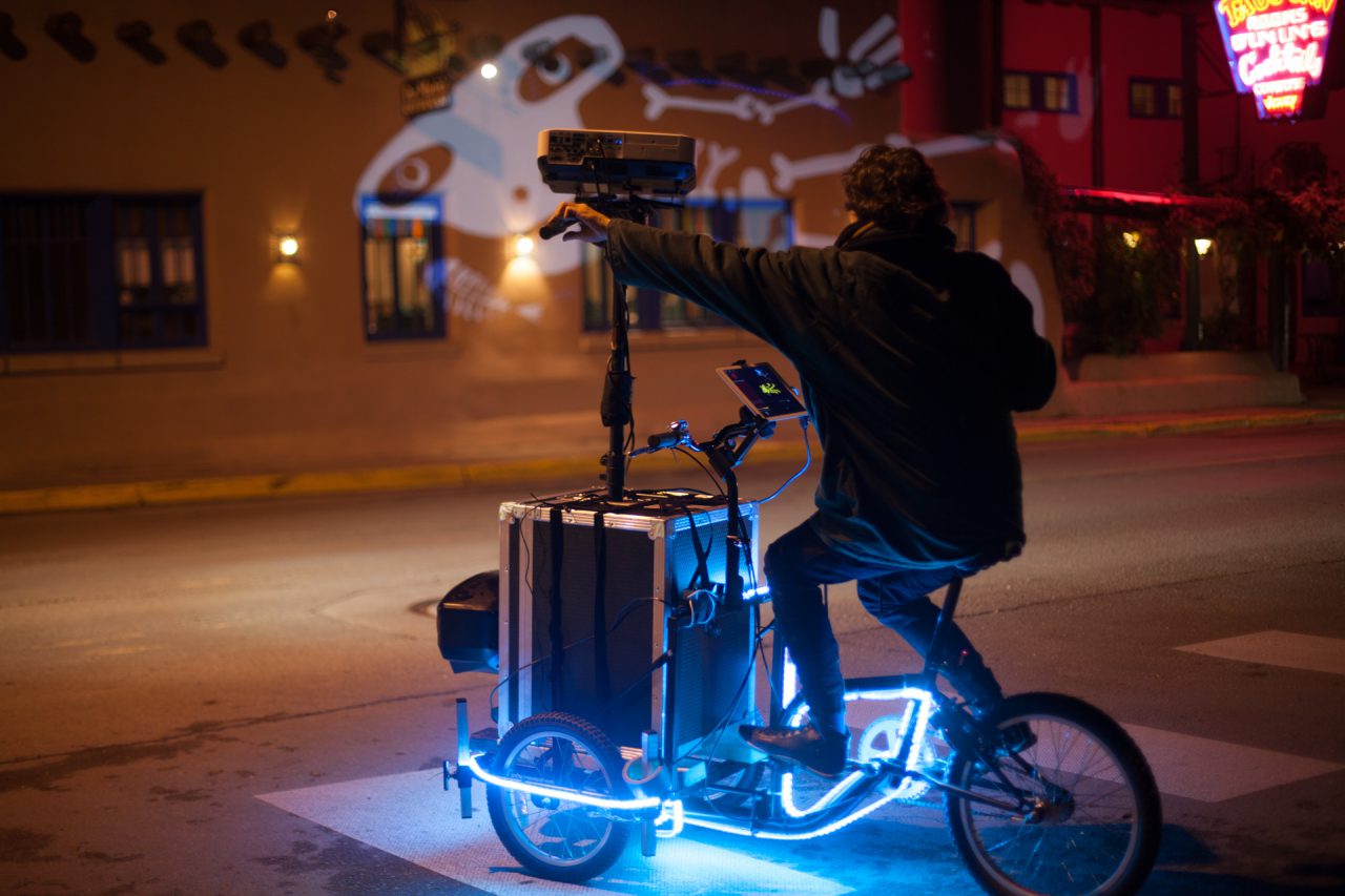 VJ Suave Suaveciclo conducting mobile projection mapping during a festival in Taos, USA.