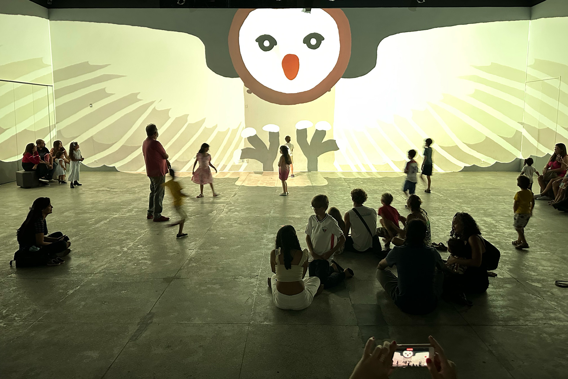 Photo inside the immersive intallation. People gathering and watching the final scene of the owl. Photography by Ygor Marotta