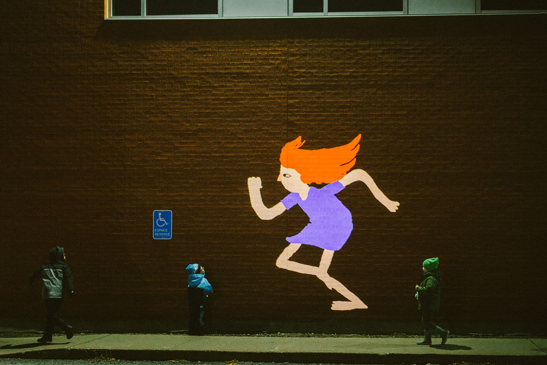 Large scale projection on a wall of a girl in 2d drawing running
